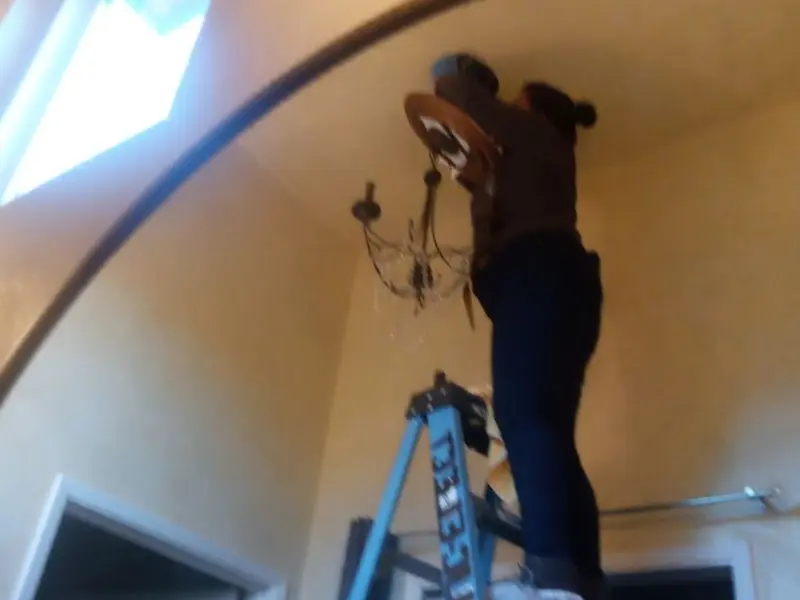 Electrician installing a chandelier in a Upper Allen residence